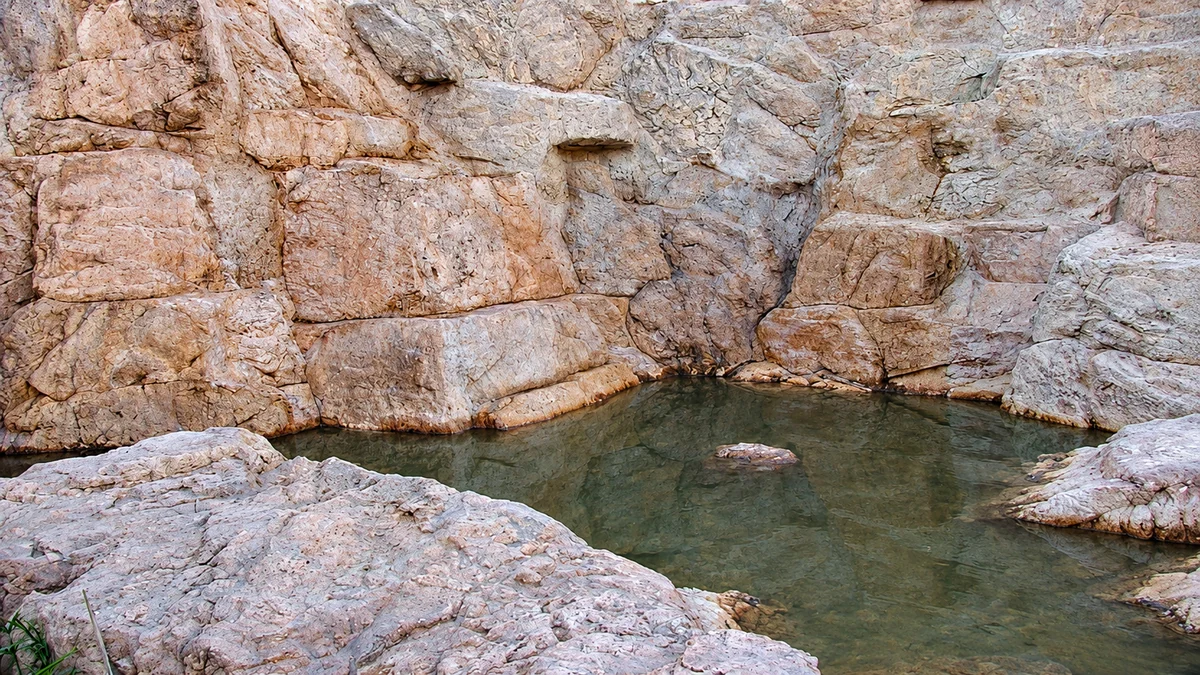 Artificial rock cliff wall enclosing a still natural-edged pool