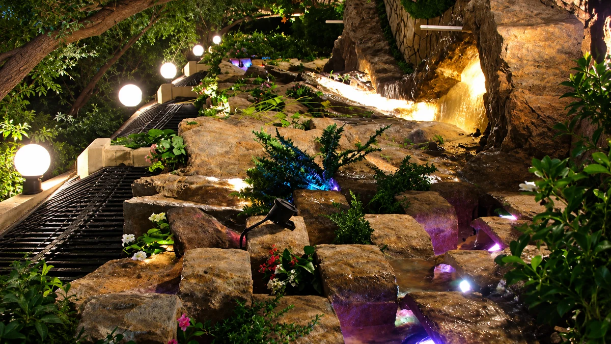 Terraced rock cascade, planted and lit with colour at night