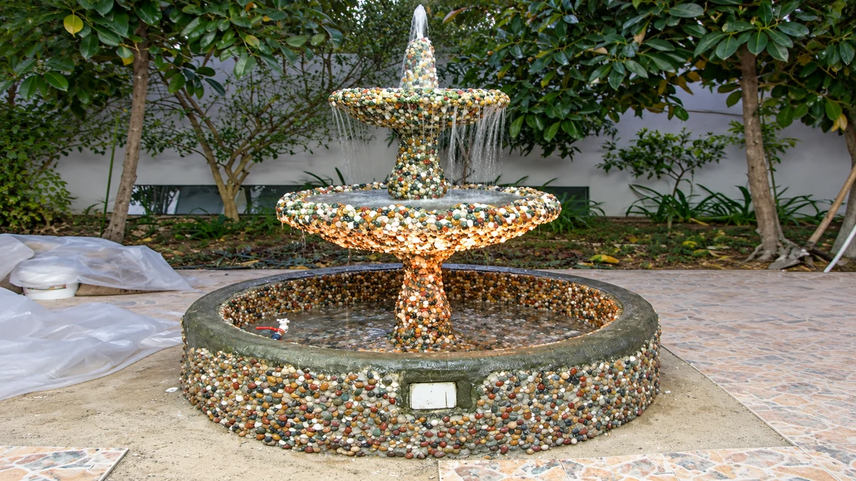 Two-tier garden fountain clad entirely in coloured river pebbles